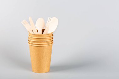 Çevresel kağıt bardaklar ve gri arka planda ahşap çatal bıçak takımı. Sürdürülebilir yaşam tarzı kavramı. sıfır atık, plastiksiz eşyalar. Plastik kirliliğini durdurun. Uzayı kopyala, şablon, Mockup. Yüksek kalite fotoğraf