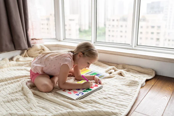 Little child english online at home. Homeschooling and distance education for kids. Girl student drawing english letters at the notebook during coronavirus covid-19 quarantine. High quality photo