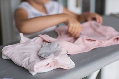 Şirin küçük kız evde giysileri ütülemeye dayanıyor. Bebek için ütü yaparken annesine yardım eden kız. Yüksek kalite fotoğraf
