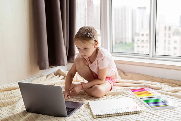 Little child english online at home. Homeschooling and distance education for kids. Girl student drawing english letters at the notebook during coronavirus covid-19 quarantine. High quality photo