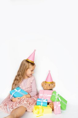 Mutlu çocuk boks gününde hediye alıyor. Küçük kız hediye kutusuyla gülümsüyor. Pembe şapkalı küçük bir çocuk beyaz arka planda izole edilmiş doğum günü hediyesi taşıyor. Boşluğu kopyala, modelle, şablon pankartı