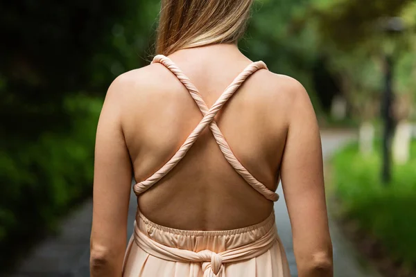 Jovem mulher elegante com cabelo loiro posando em vestido formal maxi de trás ao ar livre no verão — Fotografia de Stock