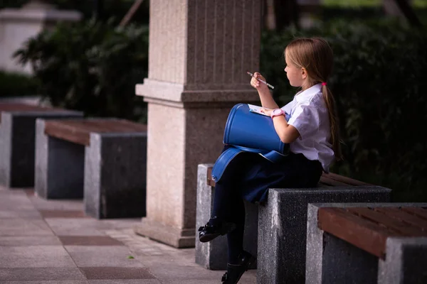 Terug naar school. Klein meisje van de basisschool buiten. Kind doet huiswerk buiten na de lessen — Stockfoto