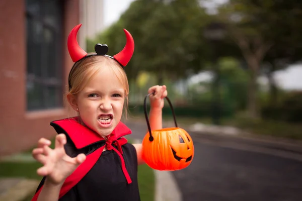 Little Girl in costume of devil with red horns outdoor. Happy Halloween concept. High quality photo