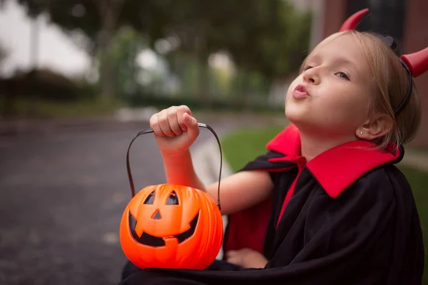 Dziewczynka w kostiumie diabła z czerwonymi rogami w parku. Szczęśliwego Halloween koncepcja — Zdjęcie stockowe