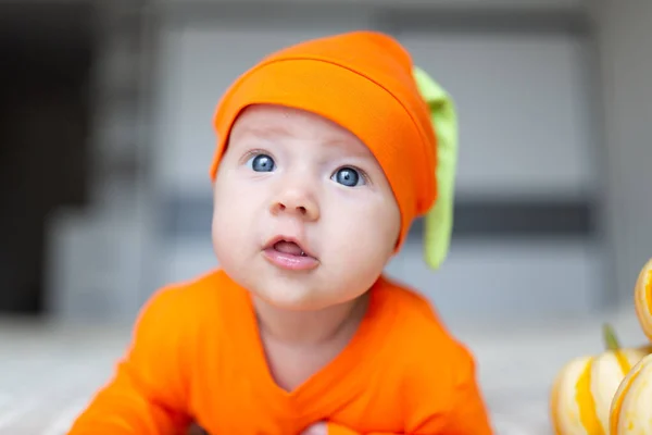 Vista de ângulo alto do bebê em traje de abóbora. Happy Kid dois meses de idade em laranja traje de Halloween na cama — Fotografia de Stock