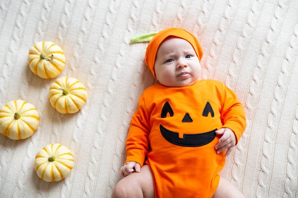 Вид с высоты угла на ребенка в костюме тыквы. Happy Kid 2 months old in orange Halloween costume on bed — стоковое фото
