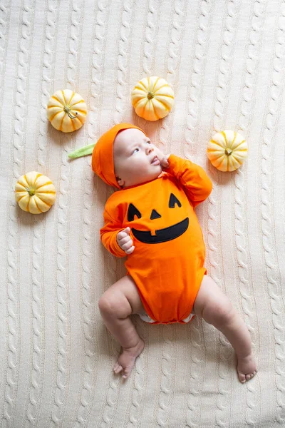 Υψηλή γωνία άποψη του μωρού σε κοστούμι κολοκύθας. Happy Kid δύο μηνών με πορτοκαλί αποκριάτικη στολή στο κρεβάτι — Φωτογραφία Αρχείου