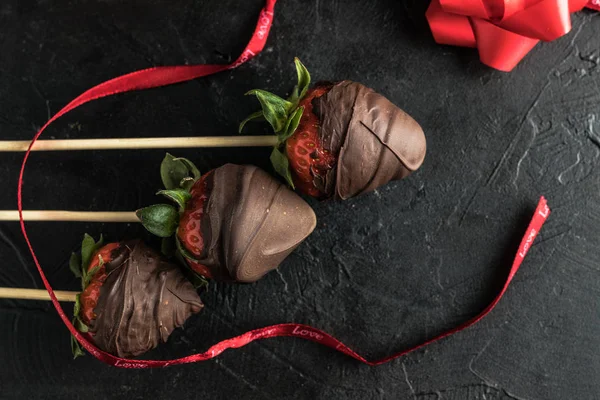 Strawberries with melted chocolate and gift ribbon — Stock Photo, Image