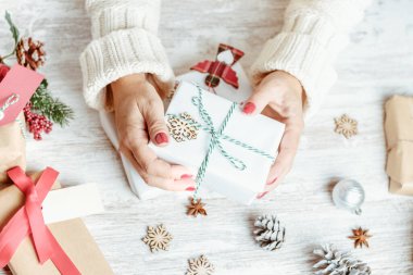 El yapımı hediyelerle dolu bir masada hediye tutan kız elleri.