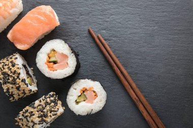 Suşi parçaları üstte ve ahşap Çin yemek çubukları üstte.