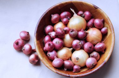 Beyaz arka planda ahşap bir kasede çok renkli soğan. Yukarıdan görünüşü.