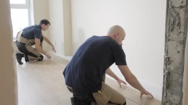 Klusjesmannen Gekleurde Jumpsuits Zetten Houten Laminaat Bord Vloer Buurt Van — Stockvideo