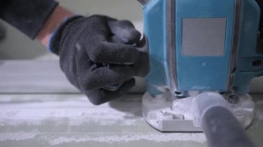 siyah eldiven deneyimli adam elektrikli yapboz kullanarak beyaz alçıpan kurulu keser