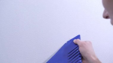 yetenekli zanaatkar özel plastik spatula yakın görünümü ile beyaz duvar kağıdı hattı aşırı tutkal alır