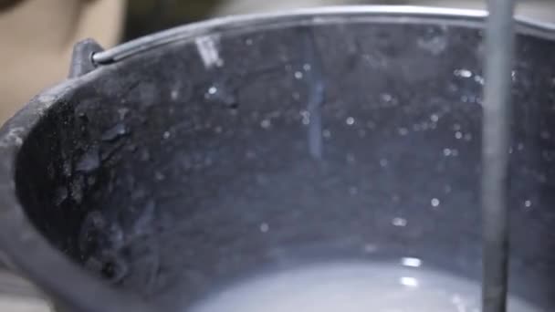 ハンディマンのクローズアップ映像は 黒いバケツで灰色の液体接着剤をミックス — ストック動画