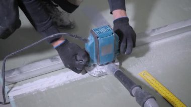 siyah eldiven deneyimli adam elektrikli yapboz kullanarak beyaz alçıpan kurulu keser