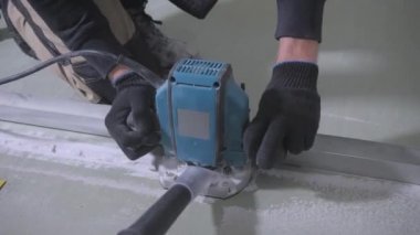 siyah eldiven deneyimli adam elektrikli yapboz kullanarak beyaz alçıpan kurulu keser