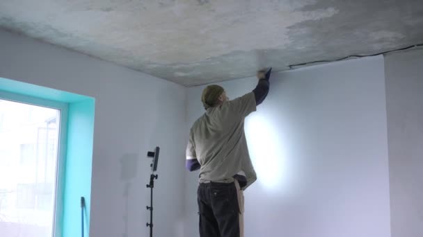 经验丰富的维修人员检查和撕掉白色壁纸边缘的墙壁照明与特殊灯在手 — 图库视频影像