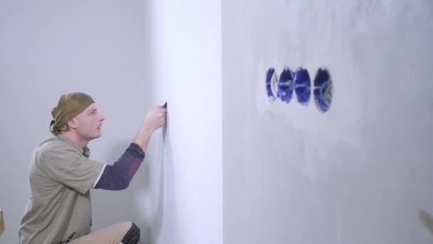 Professional Handyman Cleans Carefully White Wallpaper Edges Wall Outlet Holes — Stock Video