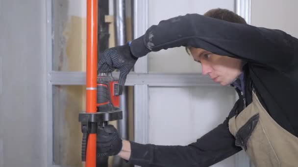修理工在黑色拉翻和棕色连身衣螺丝轮毂盖附近的橙色管道支持对窗口 — 图库视频影像