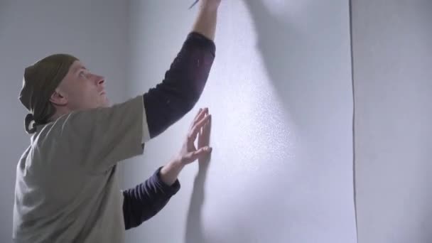 Опытный Ремонтник Комбинезоне Фиксирует Белые Обои Висящие Стене Специальным Инструментом — стоковое видео