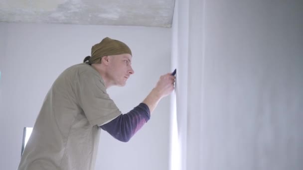Konzentrierter Handwerker Fixiert Weiße Tapetenkanten Wand Mit Speziellem Blauen Kunststoffspachtel — Stockvideo