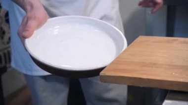 Kafe şefi beyaz tabakta altın hamurlu pizza koyar.