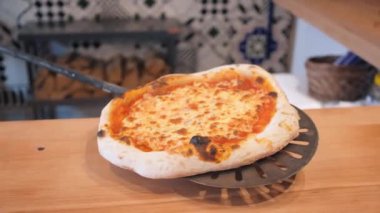 Şef pizzacıda spatulada hamurlu pizza tutuyor.