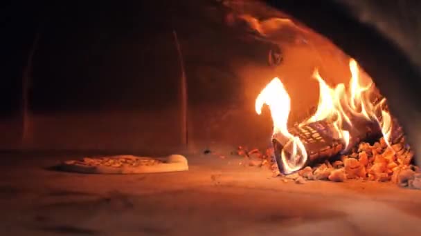 Raw pizza lies on oven stone bottom baking against wood logs — Stock Video