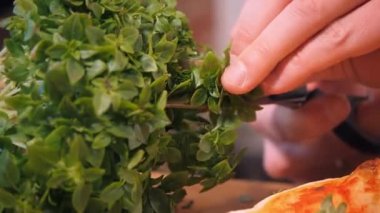 Pizzacı taze roka keser ve yemek koyar.