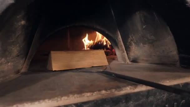 Werknemer voegt hout log in oven firebox en haalt pizza — Stockvideo