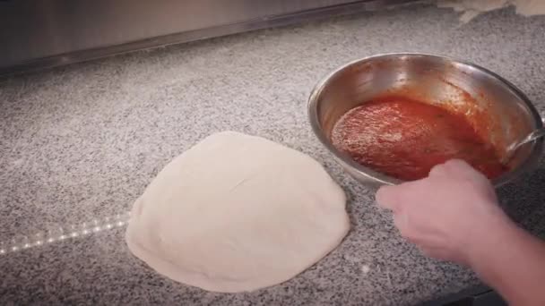 Pizza výrobce dává rajčatovou omáčku na těsto pomocí velké lžičky — Stock video