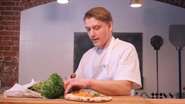 Kuchař krájí čerstvé bylinné zeleně a dává na chutnou pizzu — Stock video