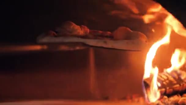 Пицца принимает блюдо с помощью лопатки и держит над пламенем — стоковое видео