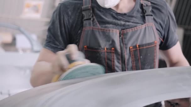 Работник в маске полирует кузов автомобиля ручным инструментом — стоковое видео