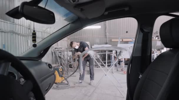 Travailleur polit pare-chocs de voiture en atelier vue du salon de l'automobile — Video