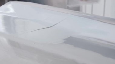 İşçi, araba gövdesine macun bıçağıyla kaplama uygular.