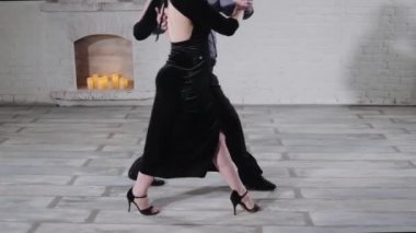 Dansçılar dekoratif şöminenin yanında Arjantin tangosu yapıyorlar.