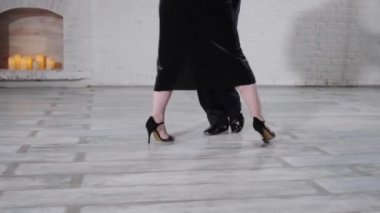 Erkekler ve kızlar beyaz duvarlarla stüdyoda ateşli tango yaparlar.