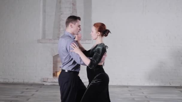 Young man and woman in elegant suits dance tango in studio — Stock Video