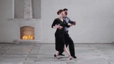 Tatil kıyafetli dansçılar odada tutkulu tango yapıyorlar.