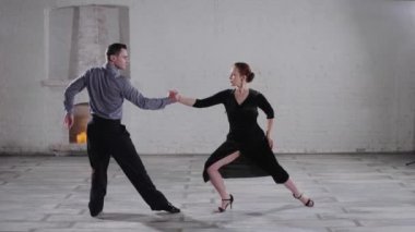 Şenlik elbiseli genç çift şöminenin yanında tango yapıyor.