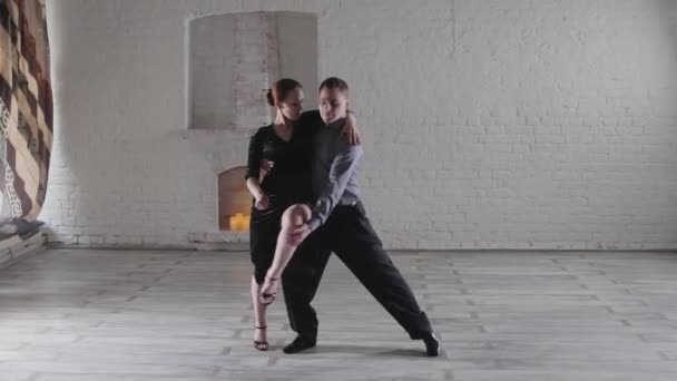 Pareja elegante baila tango caliente cerca de la chimenea decorativa — Vídeos de Stock