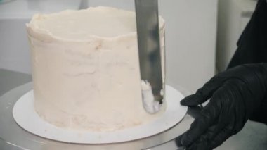 Şekerlemeci lezzetli yuvarlak pasta tarafına doğal krema sürüyor.