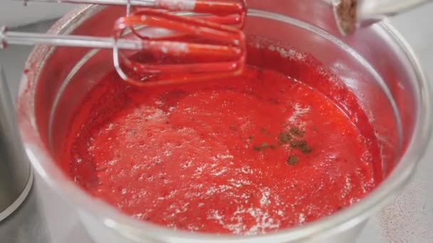 Confectioner adds cocoa powder to red dough in metal bowl — Stock Video