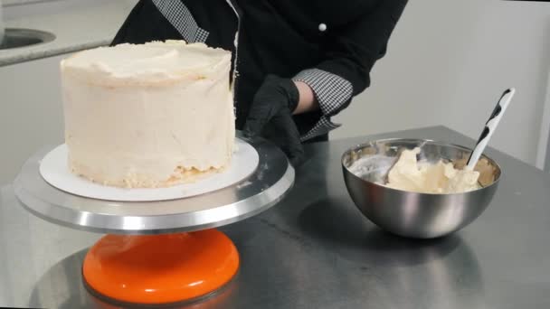 Chef cobre delicioso bolo com creme doce branco em stand — Vídeo de Stock