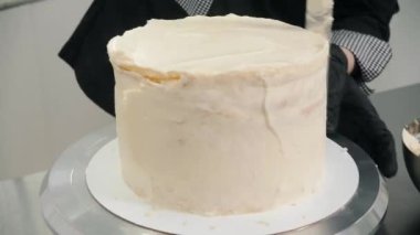 Şekerci, spatula kullanarak pastayı beyaz kremayla kaplar.