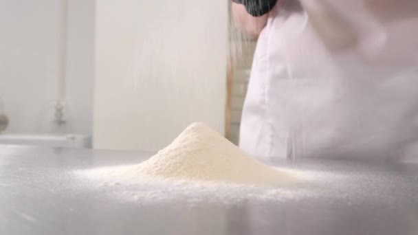 Wanita menyaring tepung gandum di tumpukan di meja logam di dapur — Stok Video