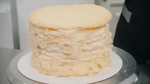 Konditor dreht Metallständer mit leckerem Kuchen am Tisch — Stockvideo